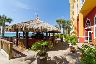 a restaurant with a straw umbrella and the ocean at Right Across The Street From Pier Park! 2 Pools Overlooking Gulf!Next To Pier in Panama City Beach