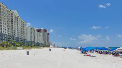 a beach with blue umbrellas and people on it at The Perfect Escape! Long Beach Resort-8th Floor-Gulf Front with AMAZING views in Panama City Beach
