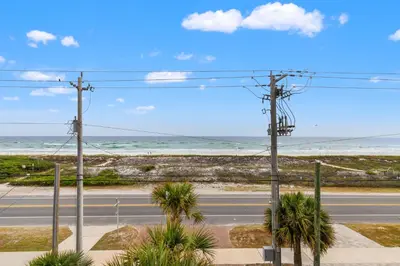 an empty road next to the ocean with palm trees at Walk To The Beach! 3 Story Home! 2 Balconies With Gulf Views! in Panama City Beach