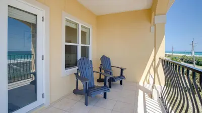 two blue chairs sitting on a balcony with the ocean at Walk To The Beach! 3 Story Home! 2 Balconies With Gulf Views! in Panama City Beach