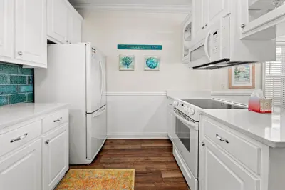 a kitchen with white cabinets and a white refrigerator at Next To Pier Park! STEPS from the Beach! Dog-Friendly! Pool! in Panama City Beach