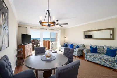 a living room with a table and a couch at Directly On The Beach! First Floor Sundeck! Near Pier Park! Sleeps 6! in Panama City Beach