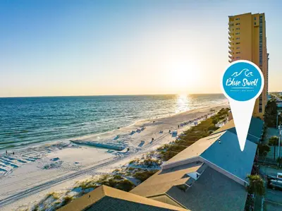 a view of a beach with a blue sand sign at Directly On The Beach! First Floor Sundeck! Near Pier Park! Sleeps 6! in Panama City Beach