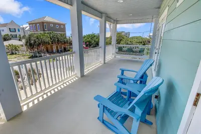 two blue chairs sitting on the front porch of a house at 5 Bed, 5 Bath Beach Home/Only a 3 Minute Walk To The Beach! SLEEPS 12 in Panama City Beach