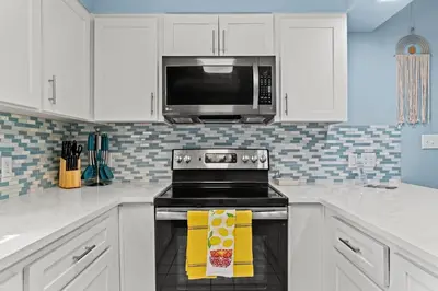 a kitchen with a stove and a microwave at Contemporary Bungalow / West End PCB / Available NOW! / Perfect for Family in Panama City Beach