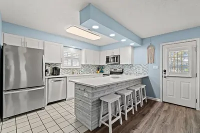 a kitchen with white appliances and blue walls at Contemporary Bungalow / West End PCB / Available NOW! / Perfect for Family in Panama City Beach