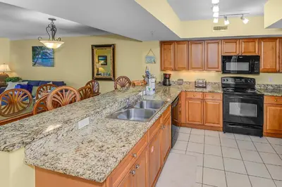 a kitchen with a sink and a stove top oven at Emerald Beach Resort Condo-Gulf Front+Beach Access! Beach Chair Service! in Panama City Beach