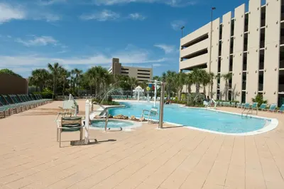 a large swimming pool with chairs and a building at Emerald Beach Resort Condo-Gulf Front+Beach Access! Beach Chair Service! in Panama City Beach