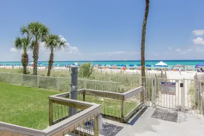 a walkway to the beach with palm trees and the ocean at Gulf Front Living Room AND Master Suite! SLEEPS 8! in Panama City Beach