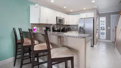 a kitchen with white cabinets and a bar with stools at Beautiful Townhome Right On The Gulf - Get Ready To Relax! in Panama City Beach