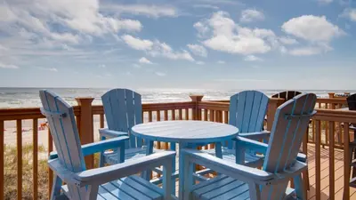 two chairs and a table on a deck with the ocean at Beautiful Townhome Right On The Gulf - Get Ready To Relax! in Panama City Beach