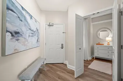a white hallway with a bench and a painting on the wall at Aqua Resort 2108 - Beach Daze in Panama City Beach
