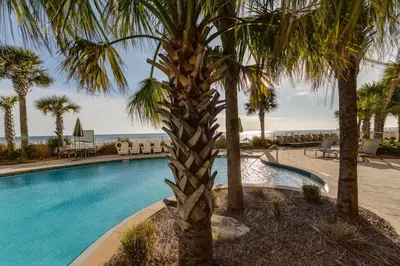 a swimming pool with palm trees next to the beach at Aqua Resort 2108 - Beach Daze in Panama City Beach