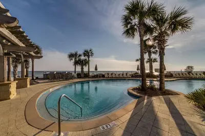 a swimming pool with palm trees and the ocean at Aqua Resort 2108 - Beach Daze in Panama City Beach