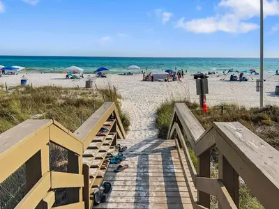 a wooden staircase leading to a beach with people at Emerald Beach Resort by Blue Swell in Panama City Beach