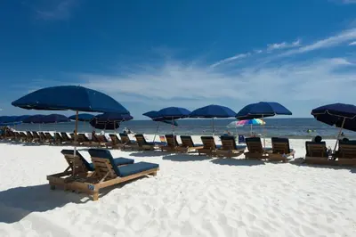 a group of chairs and umbrellas on a beach at Emerald Beach Resort by Blue Swell in Panama City Beach