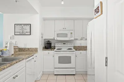 a kitchen with white cabinets and a stove and a microwave at Emerald Beach Resort by Blue Swell in Panama City Beach