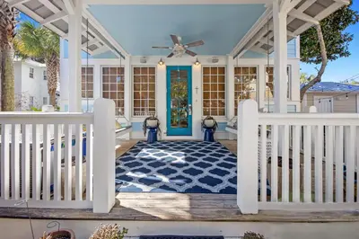 a front porch with a blue door and a ceiling fan at Quaint 2BR/25BA Cottage Nestled Between 30A & Panama City Beach! Sleeps 6! in Panama City Beach