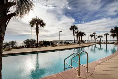a large swimming pool with palm trees in a resort at Beautiful 3rd Floor Condo w Gulf Front Master - Near Pier Park in Panama City Beach