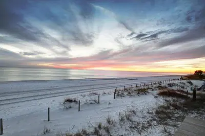 a beach covered in snow with a sunset in the background at Beautiful 3rd Floor Condo w Gulf Front Master - Near Pier Park in Panama City Beach