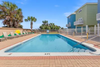 a swimming pool with chairs and a building at Across Street from Beach - Close to Pier Park - Sleeps 6! in Panama City Beach