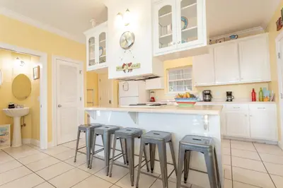 a kitchen with white cabinets and bar stools at Across Street from Beach - Close to Pier Park - Sleeps 6! in Panama City Beach