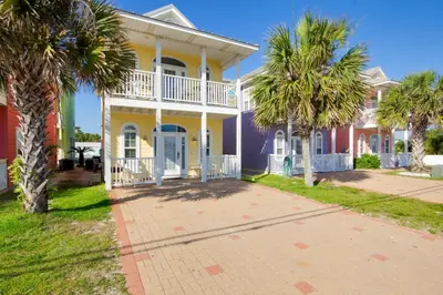 a yellow house with palm trees in front of it at Across Street from Beach - Close to Pier Park - Sleeps 6! in Panama City Beach