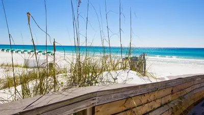 a wooden fence on a beach with the ocean at Across Street from Beach - Close to Pier Park - Sleeps 6! in Panama City Beach