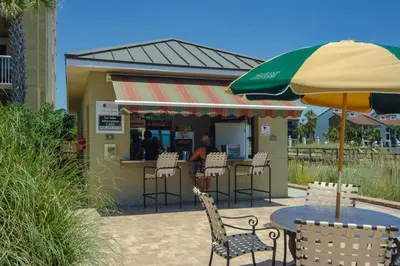 a restaurant with tables and chairs and an umbrella at Come See Why This Is The Best Condo At Grand Panama! Rooftop Pool+Tiki Bar in Panama City Beach