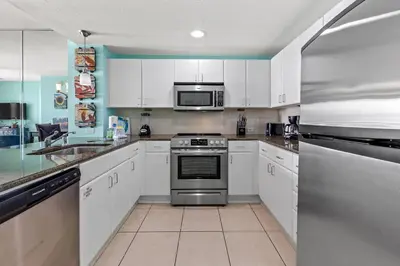 a kitchen with white cabinets and a stainless steel oven at Come See Why This Is The Best Condo At Grand Panama! Rooftop Pool+Tiki Bar in Panama City Beach