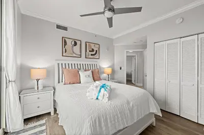 a bedroom with a white bed with two night stands and two lamps at Luxury Beachfront Condo w/ 2 Balconies! Sleeps 8! Walk to Pier Park! in Panama City Beach