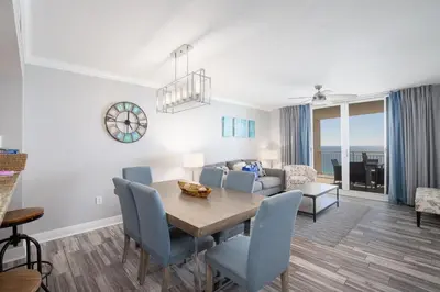 a dining room and living room with a table and chairs at Brand New Throughout! Emerald Beach - Gulf Front! Sleeps 8! in Panama City Beach