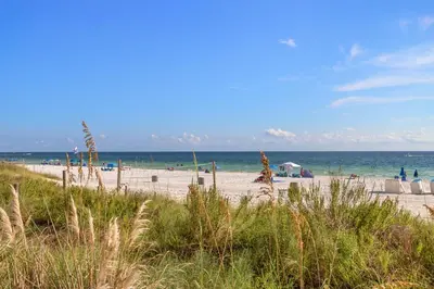 a beach with people and the ocean in the background at 20th Floor Condo! Sleeps 8! Gulf Front Master Suite w/ Beautiful Gulf Views! in Panama City Beach