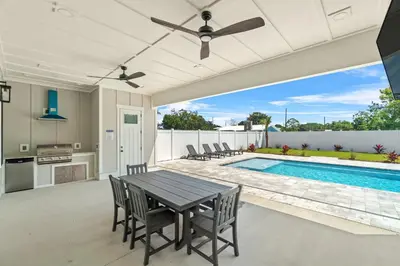 a patio with a table and chairs and a swimming pool at Brand New Home with In-ground Pool, Four Houses From Beautiful Laguna Beach in Panama City Beach