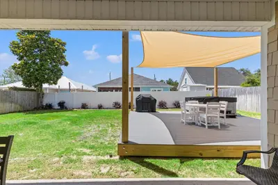 a patio with chairs and a grill in a yard at Amazing New 3br/2ba Laguna Beach! / 6p GOLF CART: 2 mins to Beach/West PCB in Panama City Beach