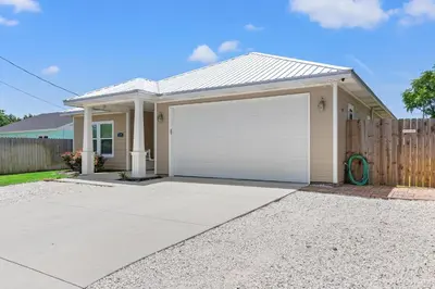 a house with a white garage with a fence at Amazing New 3br/2ba Laguna Beach! / 6p GOLF CART: 2 mins to Beach/West PCB in Panama City Beach
