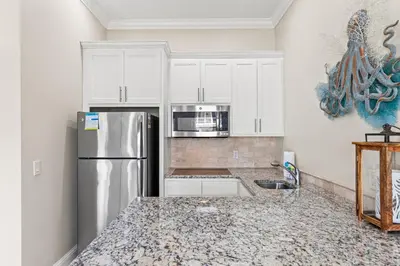 a kitchen with white cabinets and a stainless steel refrigerator at 2 Gulf View Balconies! 3 Story Townhome With 4 Bedrooms, 4 Bathrooms! Sleeps12 in Panama City Beach