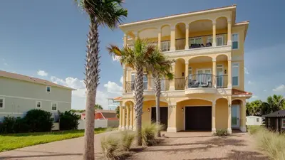 a yellow house with palm trees in front of it at 2 Gulf View Balconies! 3 Story Townhome With 4 Bedrooms, 4 Bathrooms! Sleeps12 in Panama City Beach