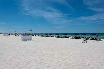 a group of people sitting on a beach with umbrellas at Rooftop Views of The Gulf! 1800 Square Foot Private Rooftop Terrace! in Panama City Beach