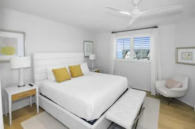 a white bedroom with a bed and a chair at Private Pool, Gulf Views & Luxurious Features Throughout this Lovely Residence condo in Panama City Beach
