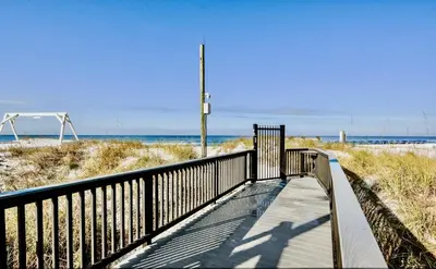 a boardwalk to the beach with the ocean in the background at Newly Renovated Beachfront Condo! Free Beach Chair Service! by Dolce Vita Getaways PCB in Panama City Beach