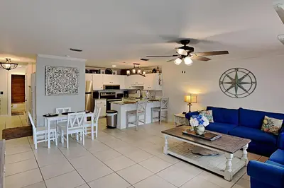 a living room with a blue couch and a kitchen at Wendwood #E2 in Panama City Beach