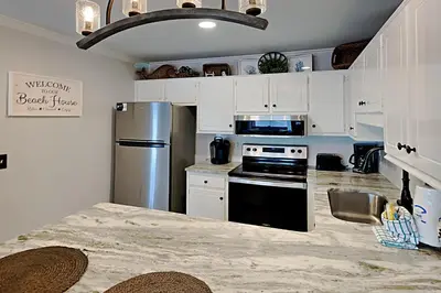 a kitchen with white cabinets and a stainless steel refrigerator at Wendwood #E2 in Panama City Beach