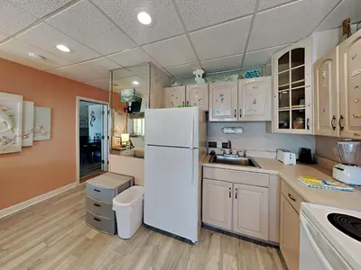 a kitchen with white cabinets and a white refrigerator at Continental 319-320 in Panama City Beach