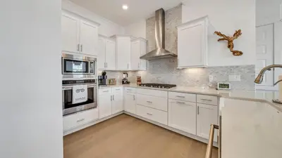 a white kitchen with white cabinets and white appliances at Current Affairs Brand New 2 BR Townhome in Prominence Golf Cart Included in Inlet Beach