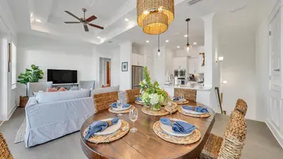 a dining room and living room with a table and chairs at Current Affairs Brand New 2 BR Townhome in Prominence Golf Cart Included in Inlet Beach