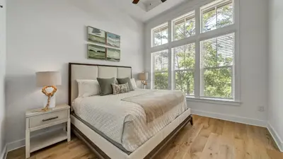 a white bedroom with a bed and two windows at Aint Nothin Wrong With Getting Your Sun Daze On in Panama City Beach