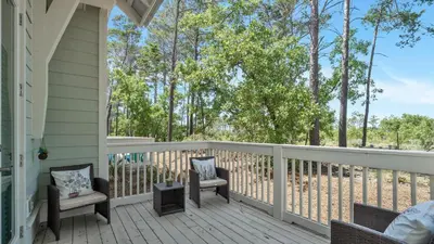 a porch with chairs and a railing with trees at Aint Nothin Wrong With Getting Your Sun Daze On in Panama City Beach