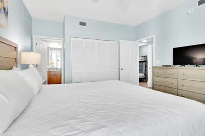 a bedroom with a large white bed and a tv at Aqua Resort 811 in Panama City Beach