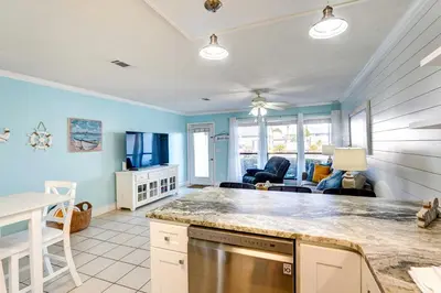 a kitchen with a counter top and a living room at Walkable Panama City Beach Condo with Pool Access! in Panama City Beach